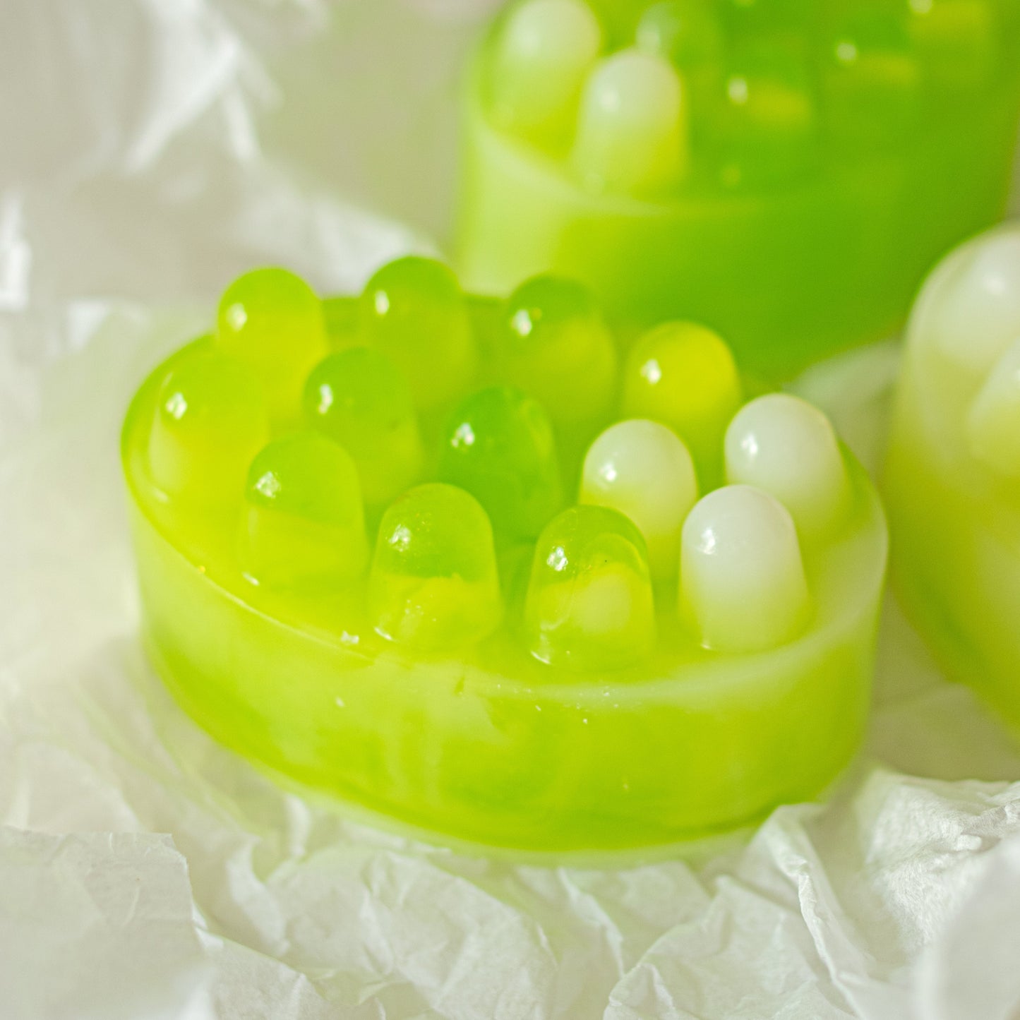 Green jelly-like soap bar with small white pearls on a white background