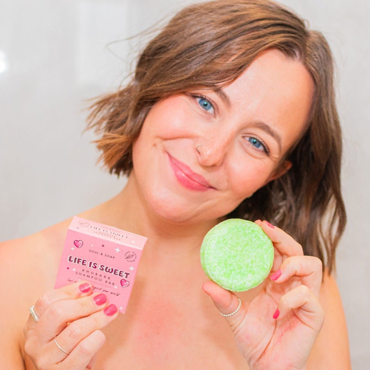 Woman holding a pink packet labeled 'Life is Sweet' and a green cookie.