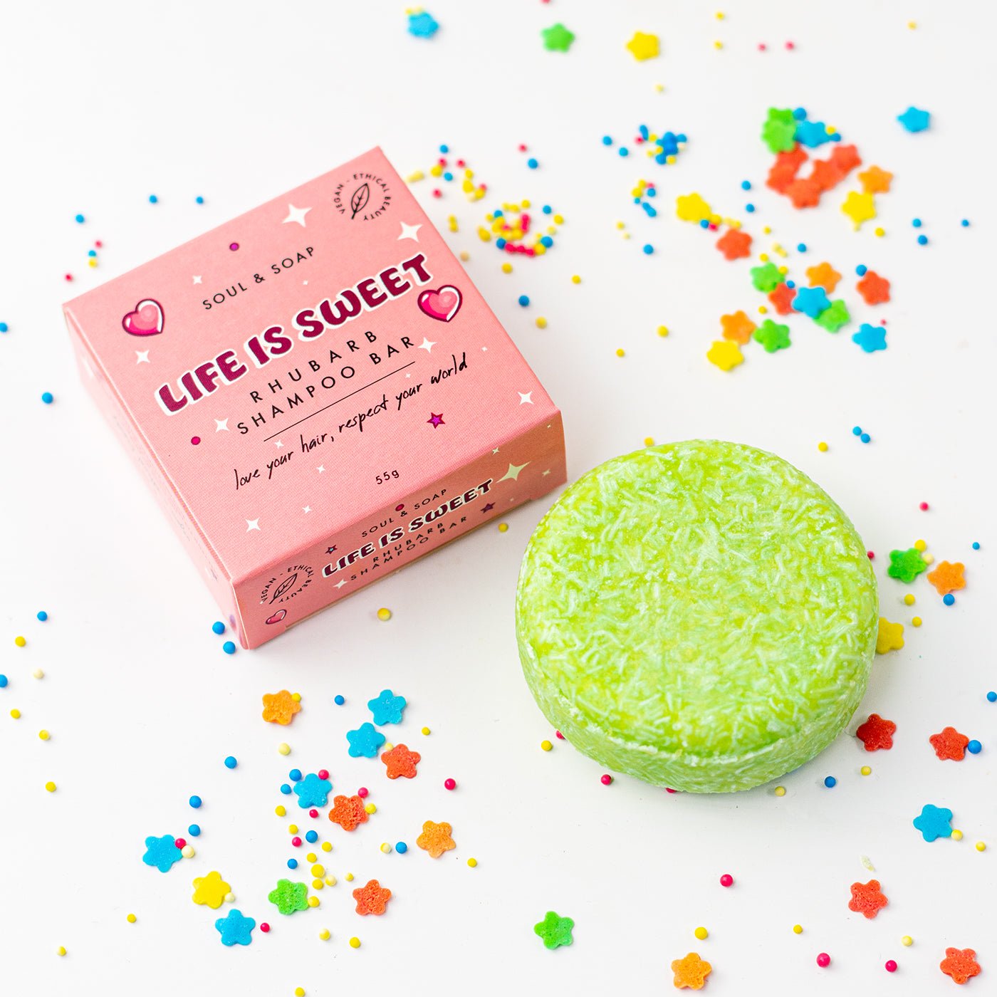Green shampoo bar with pink packaging labelled 'Life is Sweet' on a white background with colourful stars.