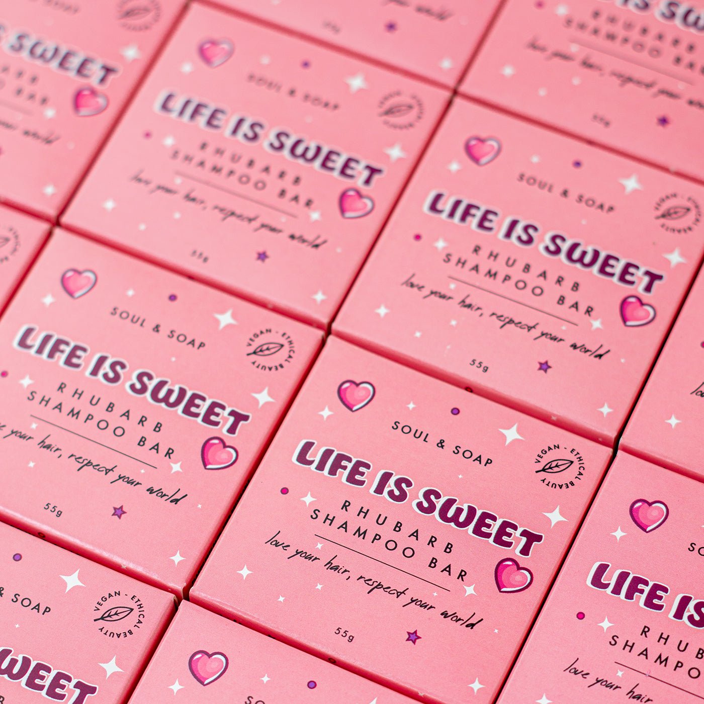 Multiple boxes of 'Life is Sweet' shampoo bars with pink packaging.