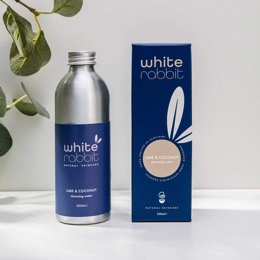White Rabbit skincare bottle and packaging on a white surface with a plant in the background