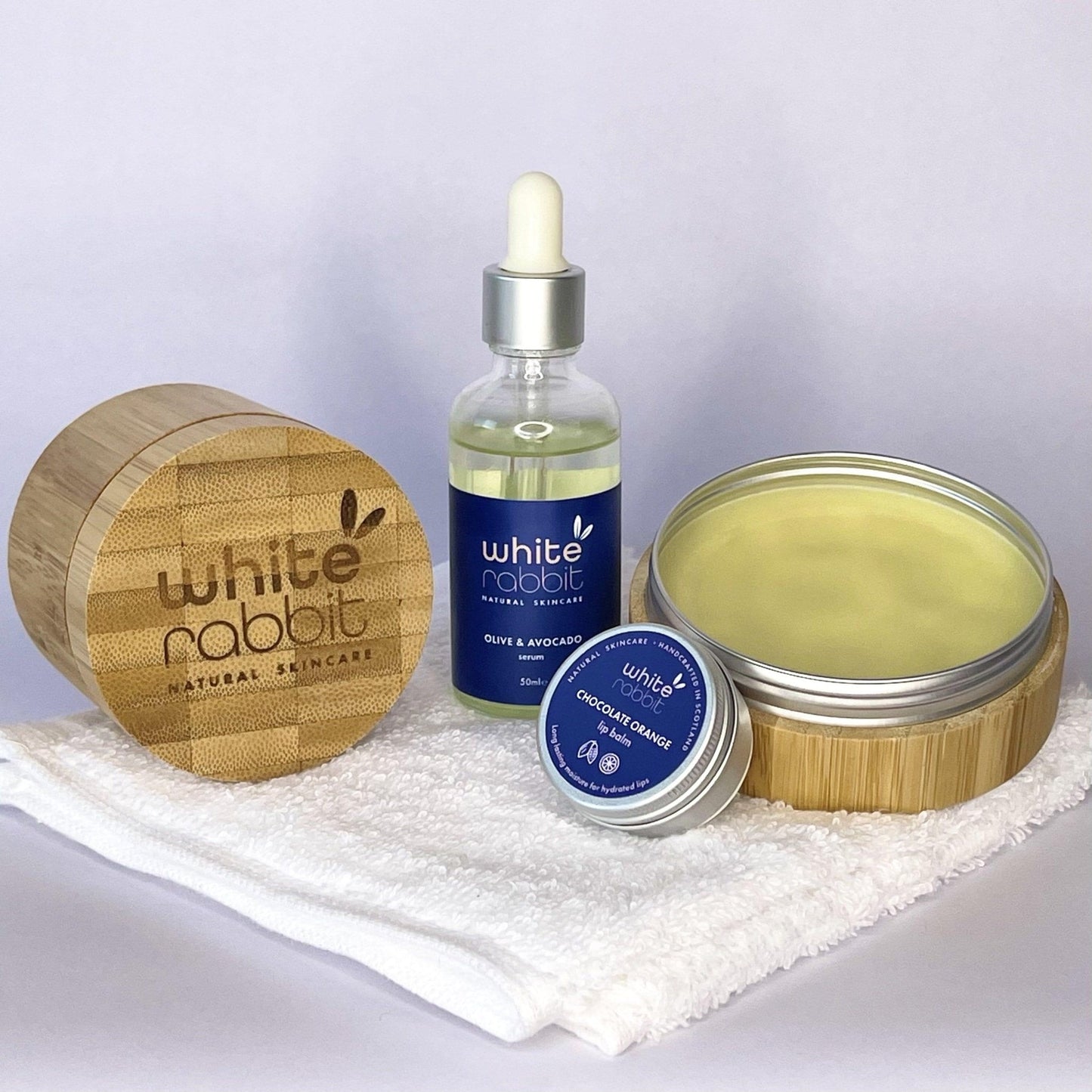 White Rabbit skincare products including a wooden container, bottle, and jars on a white background.