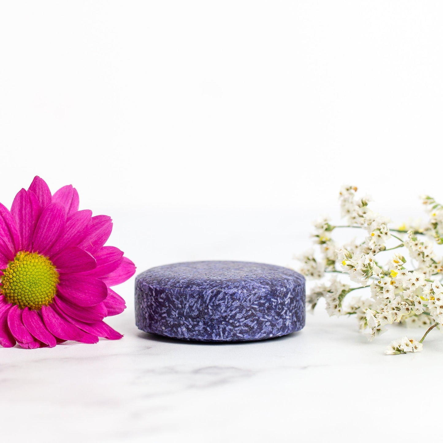 Purple bar of soap with a pink flower and white flowers on a white background