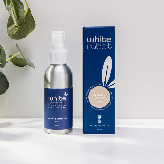 White Rabbit skincare bottle and packaging on a white surface with a plant in the background