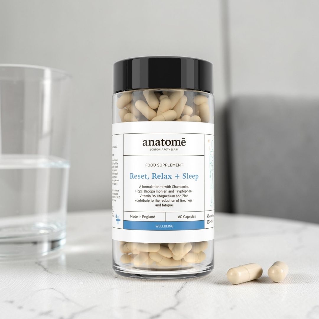 Supplement bottle labeled 'anatome' with capsules on a marble surface.