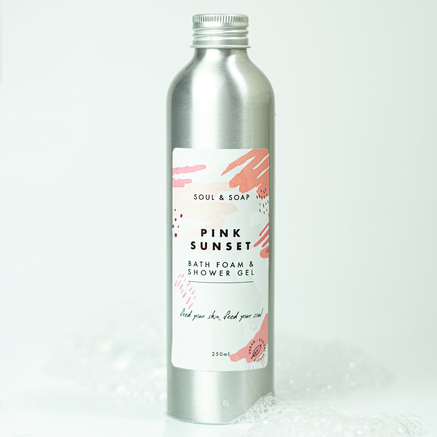 Silver bottle of 'Pink Sunset' bath foam and shower gel with a label on a white background.