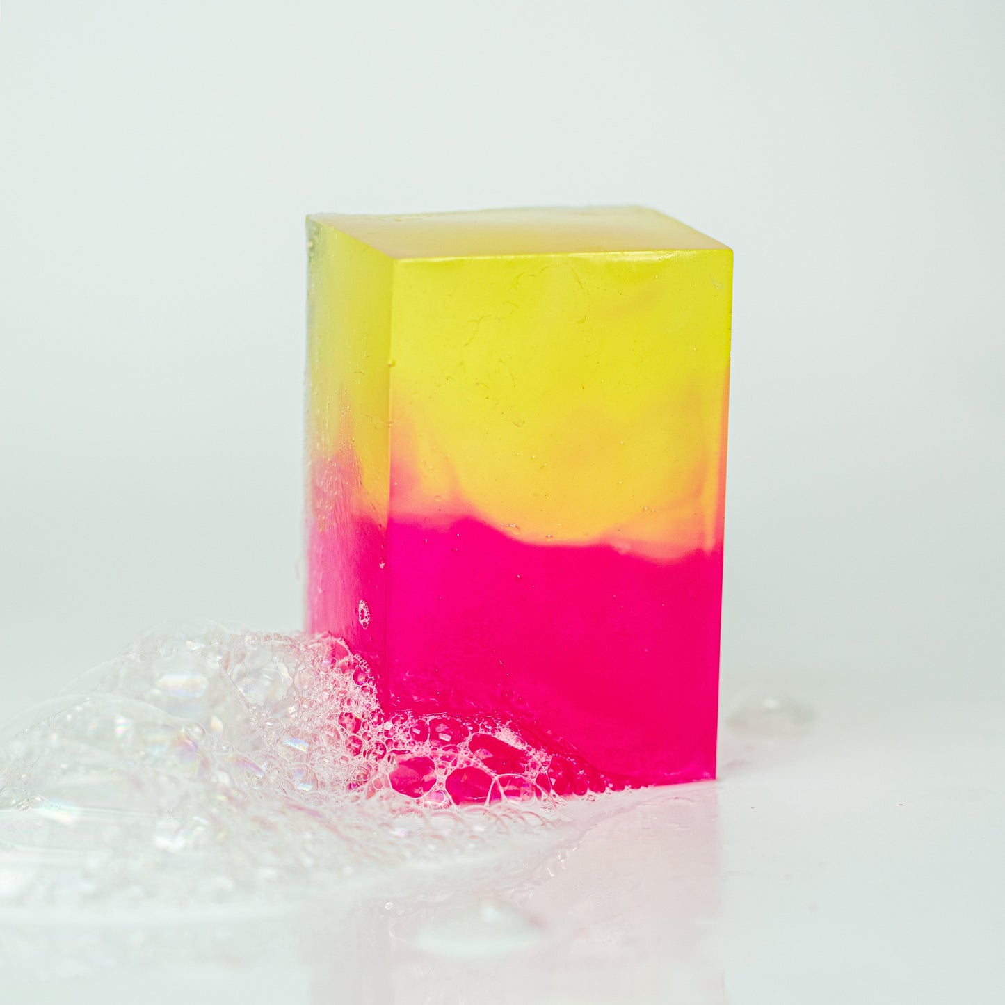 Colourful soap bar with a gradient from yellow to pink on a white background