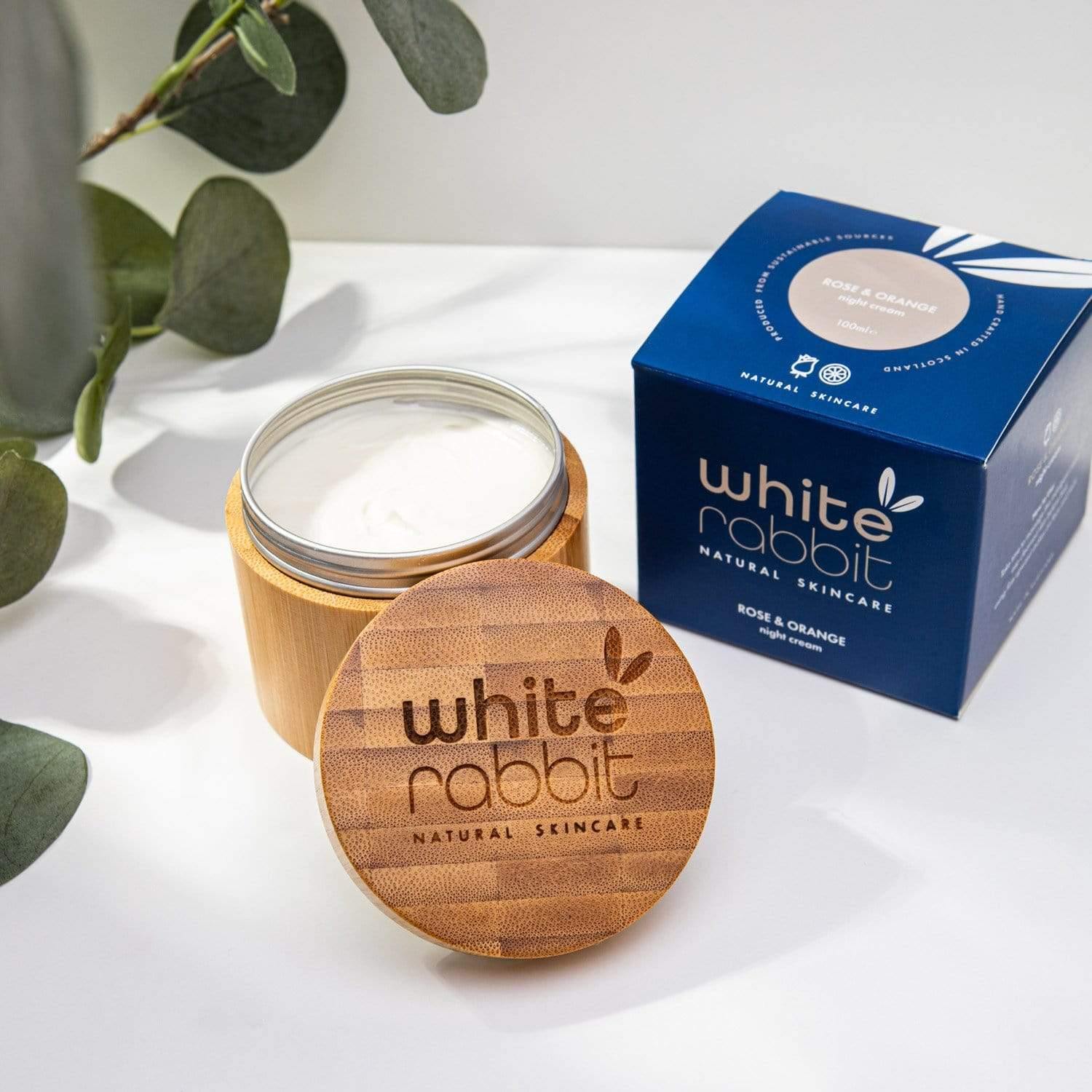 White Rabbit natural skincare jar and box on a white surface with green leaves.