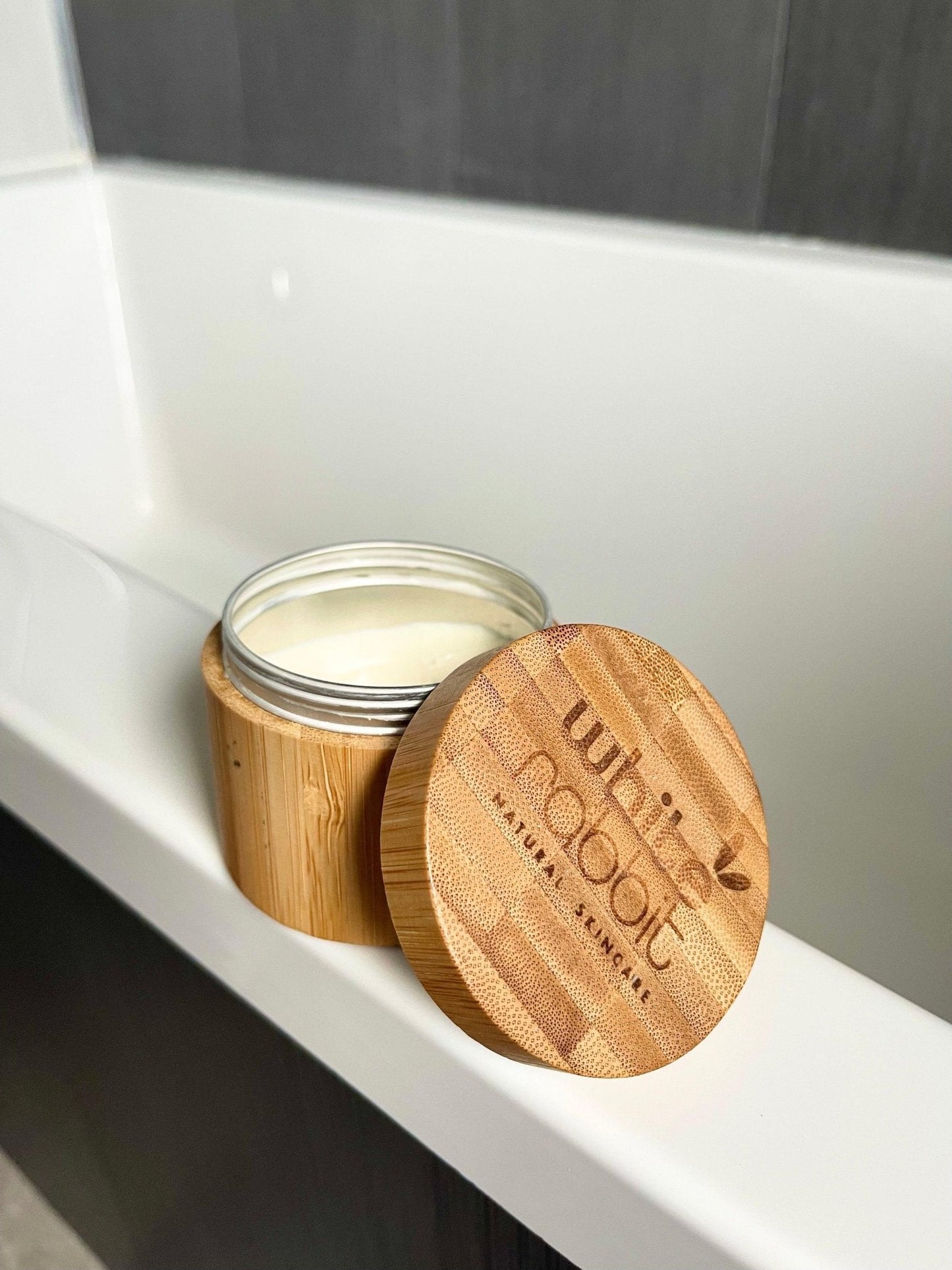Jar of cream with a wooden lid on a white surface, branded 'wubba naturals'.