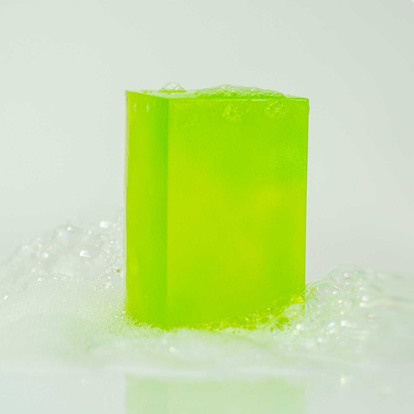 Green bar of soap with bubbles on a light gray background