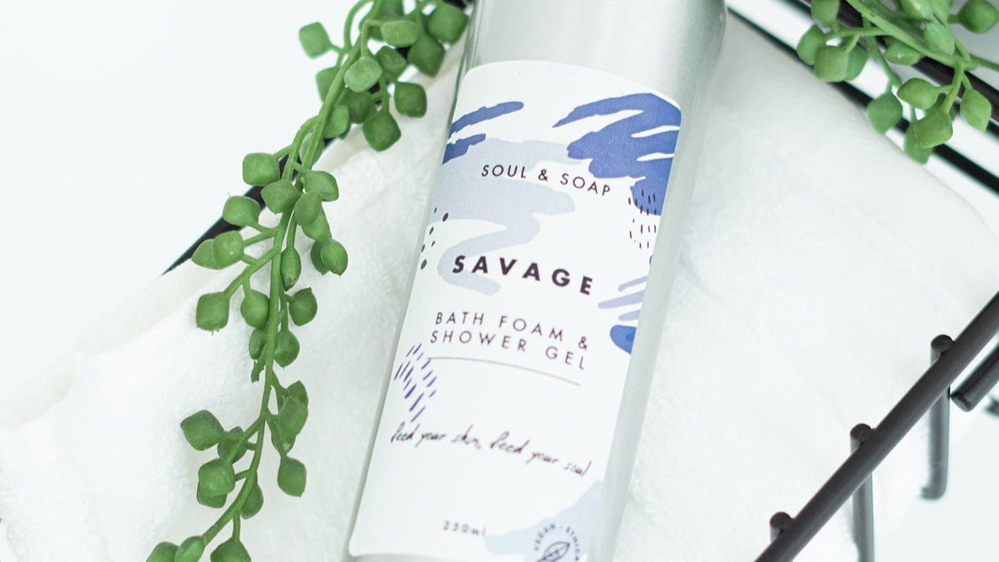 Bottle of 'Savage' bath foam and shower gel with green leaves on a white background