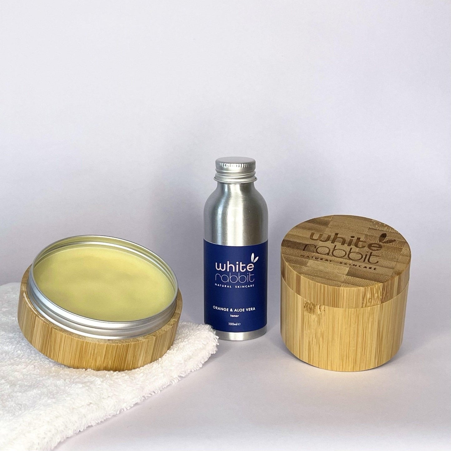 White Rabbit skincare products including a jar, bottle, and wooden container on a white background