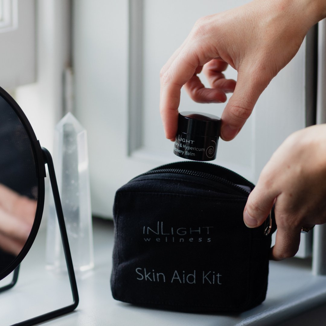 Person reaching into an Inlight Beauty Skin Aid Kit with a small bottle.