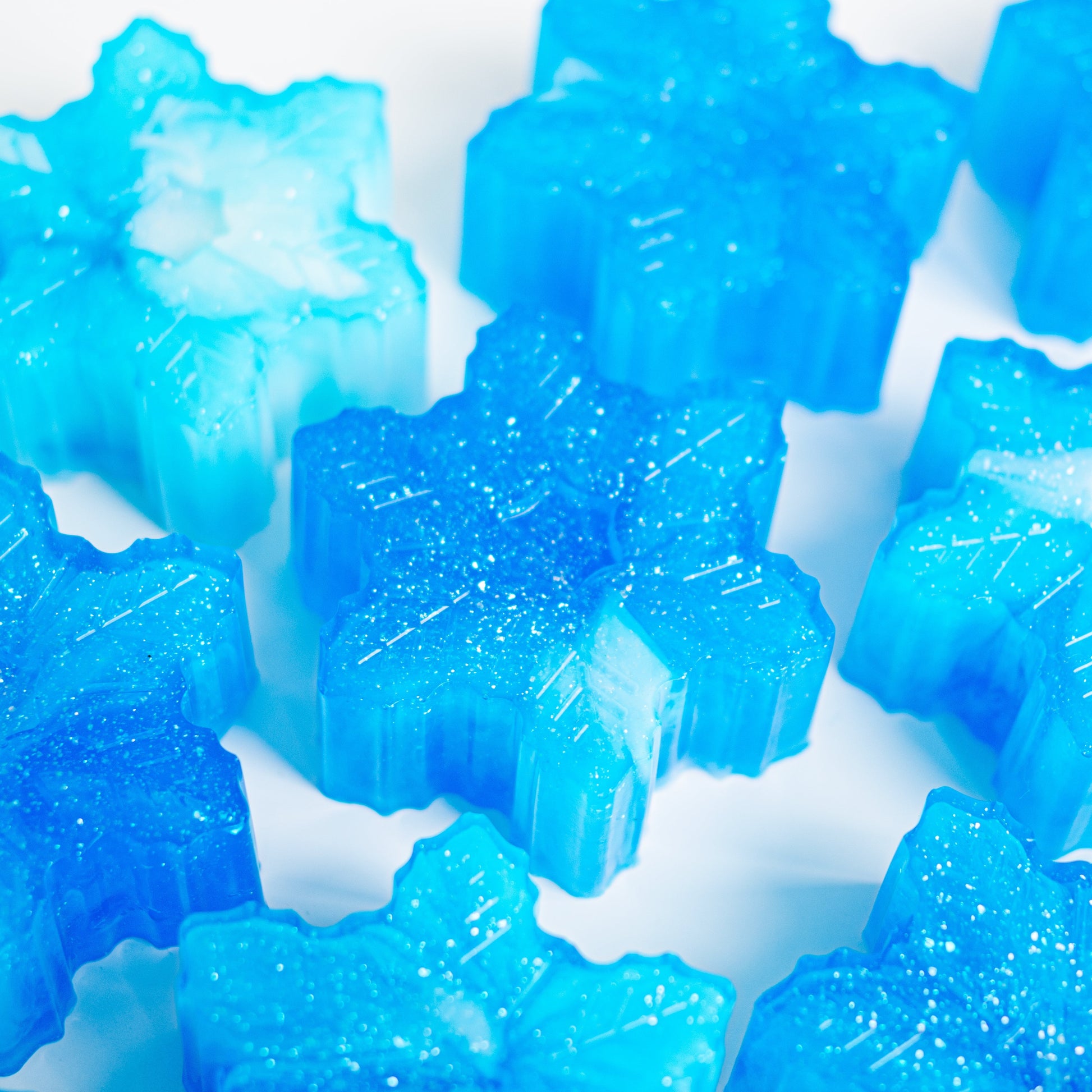 Blue snowflake-shaped soaps with sparkles on a white background