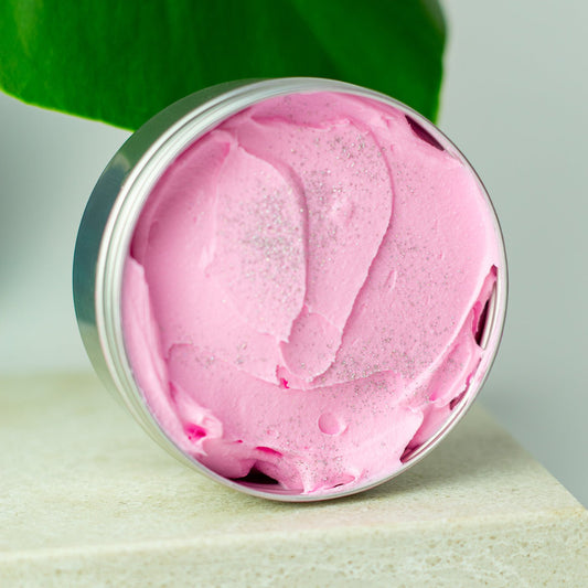 Pink cream in a silver jar with green leaves in the background