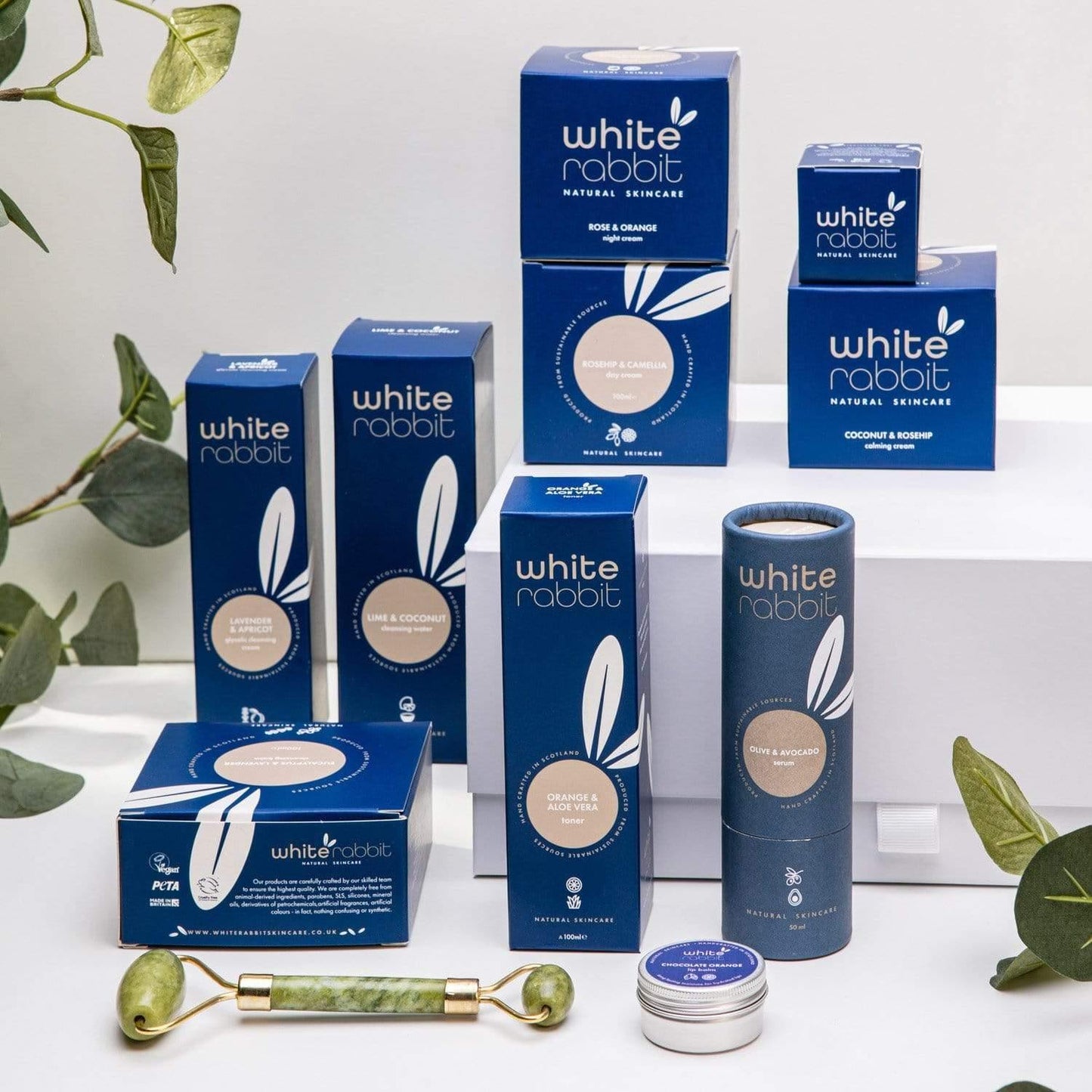 White Rabbit skincare products on a white background with green leaves.