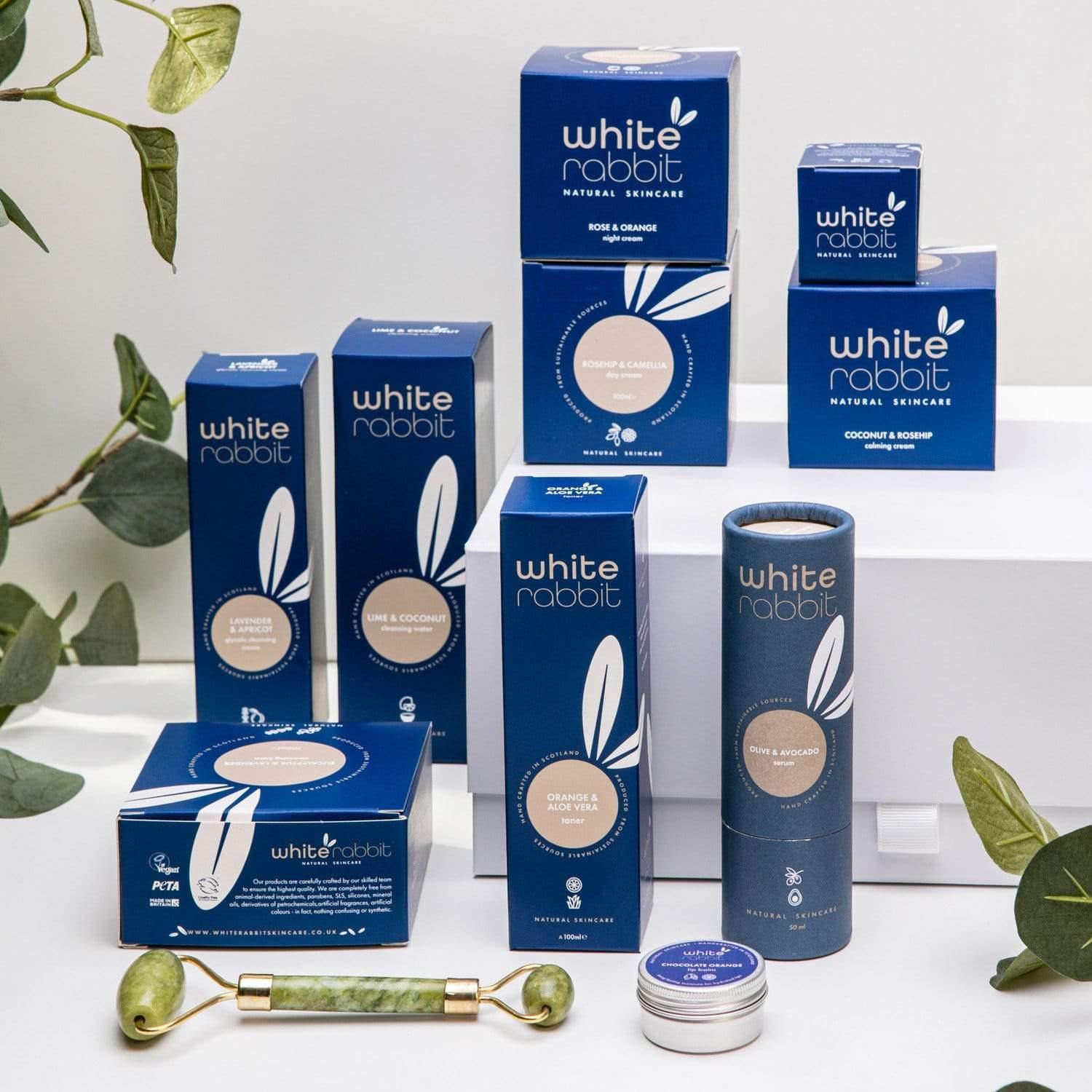 White Rabbit skincare products on a white background with green leaves.