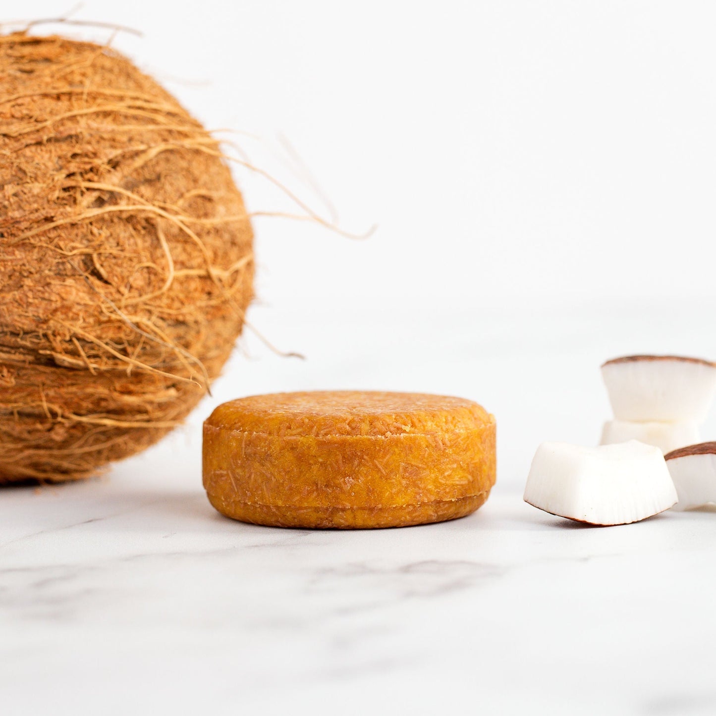 Coconut soap bar with a whole coconut and white containers on a light background