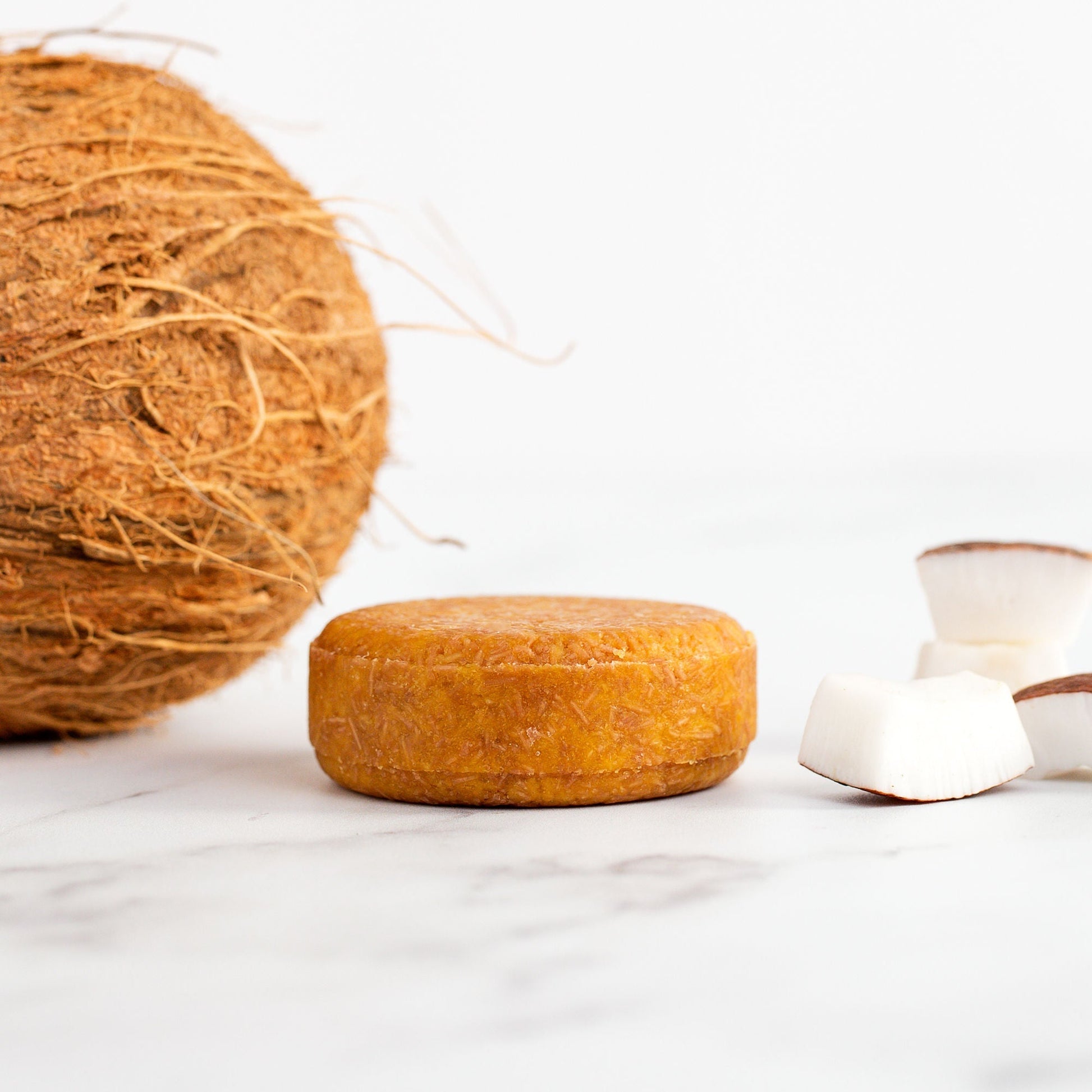 Coconut soap bar with a whole coconut and white containers on a light background